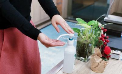 mulher higieniza mãos com álcool gel