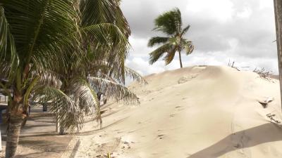 Ventos fortes movimentam dunas e areia avança no calçadão da Litorânea