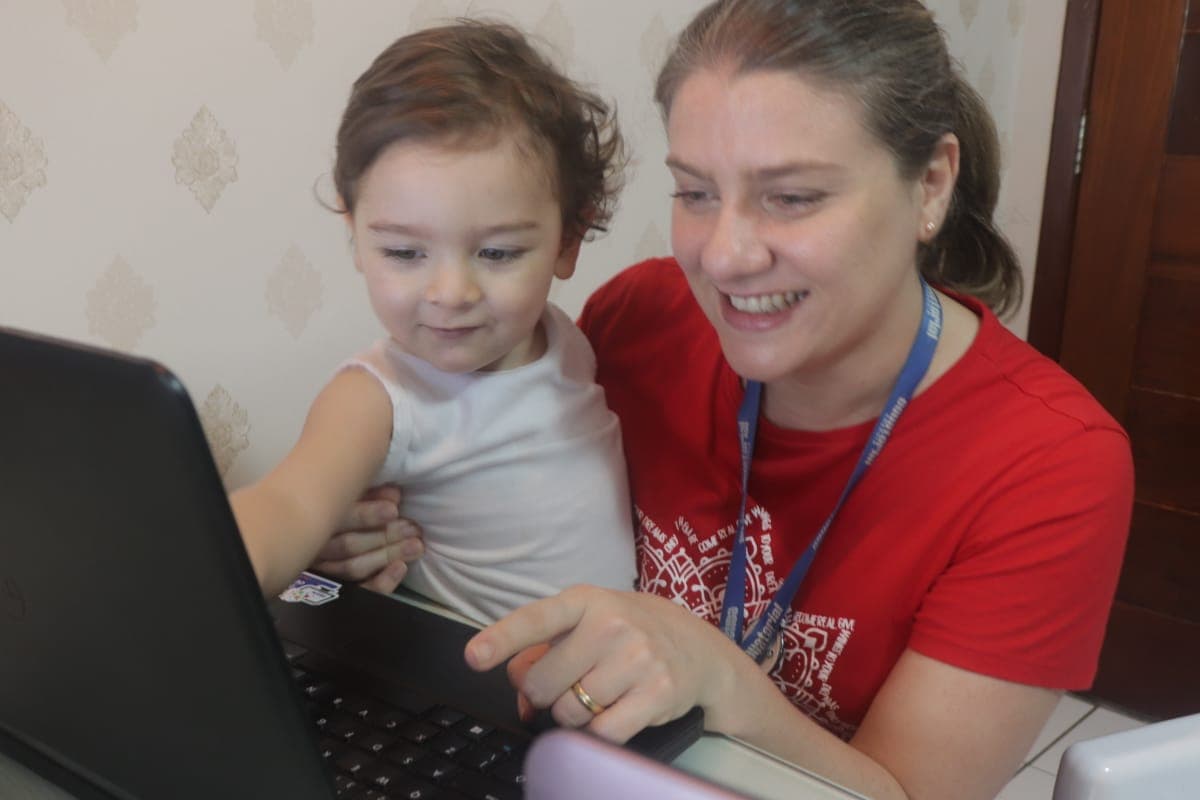 mulher e criança olham tela de computador