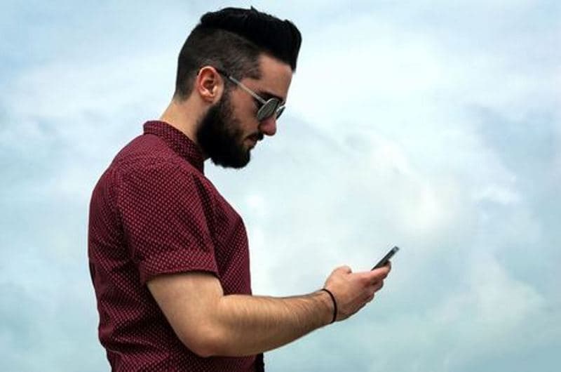 homem olha para smartphone