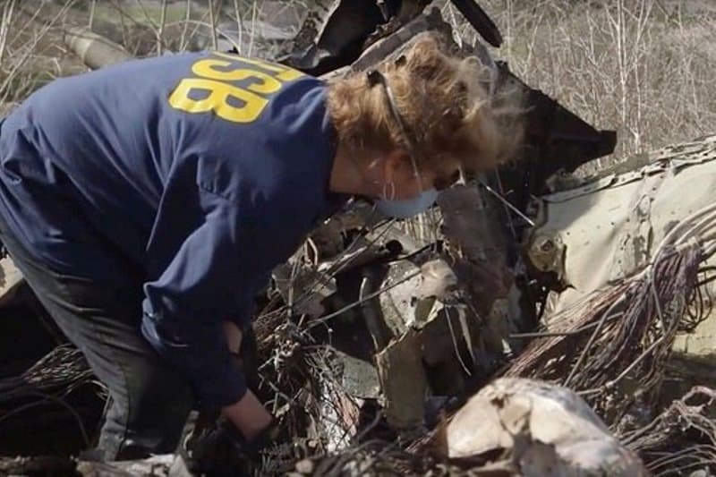 mulher analisa destroços de helicóptero
