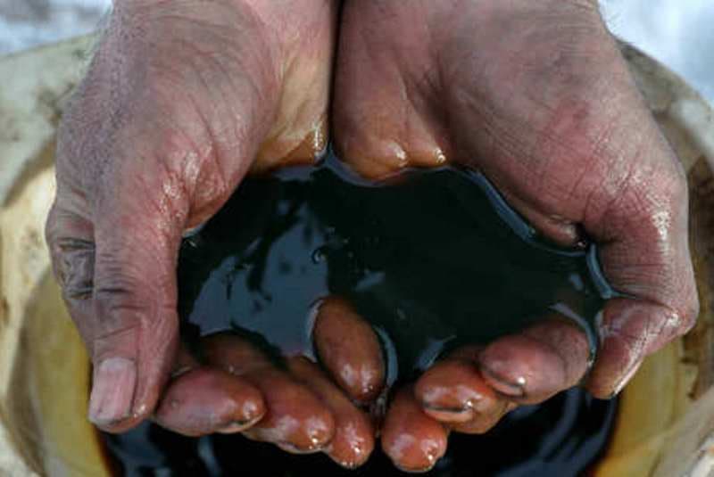 mãos erguem porção de petroleo